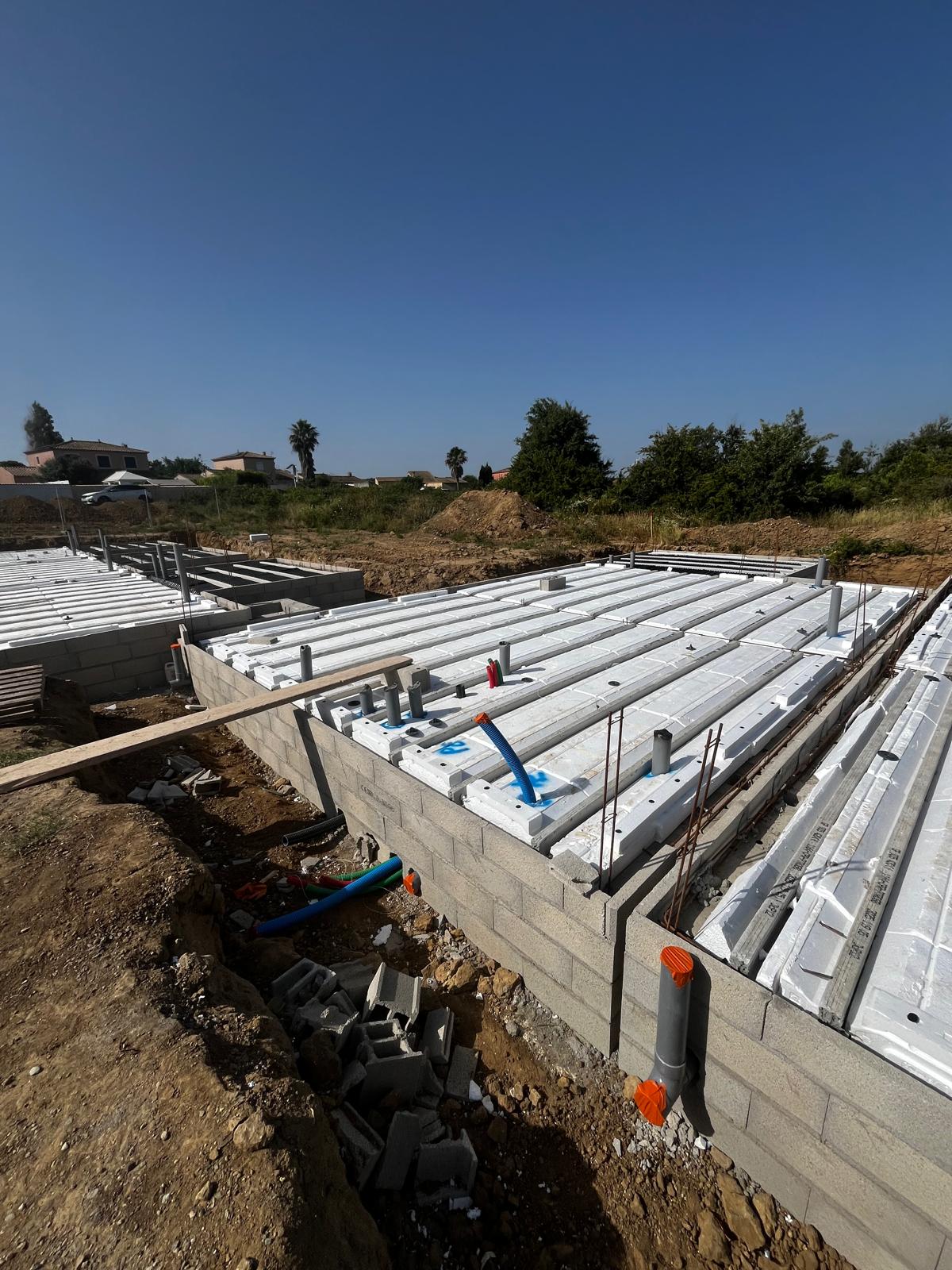 Construction d'une dalle de sol sur vide sanitaire avec hourdis polystyrène, soubassement par blocs béton, tuyauterie en attente.